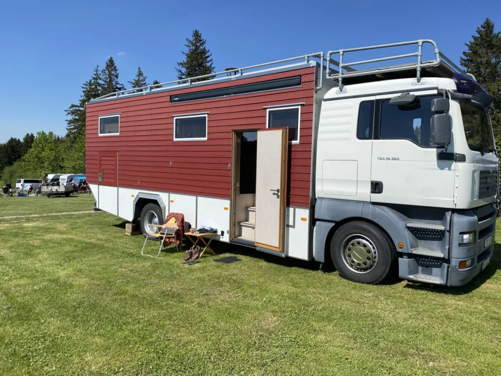 Das TinyHouse Mobil mit geöffneter Eingangstür auf der Wiese