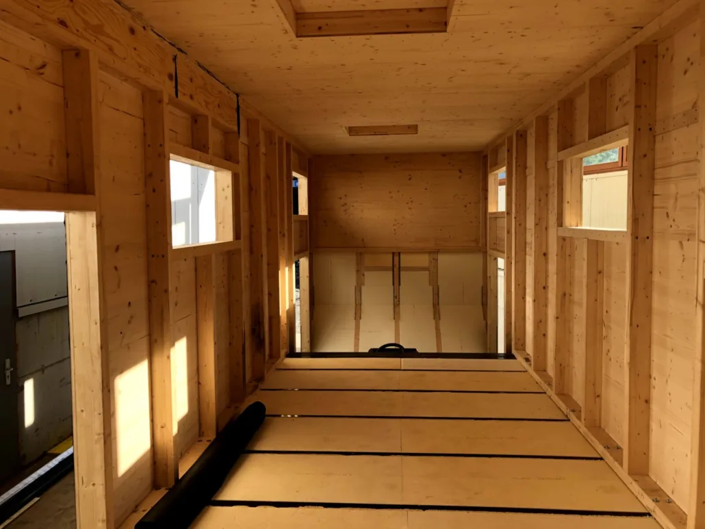 Innenraum im Rohbau: Wandständer und Holzdecke im Sonnenlicht