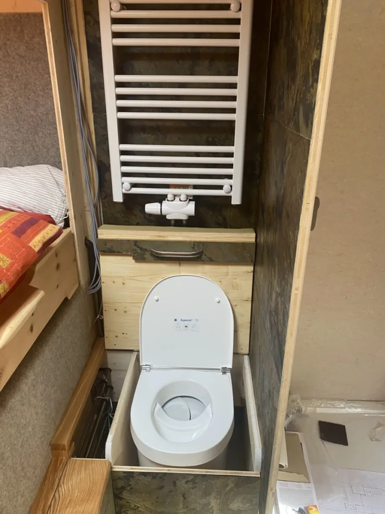 Eingebaute Trenntoilette unter dem Handtuchheizkörper