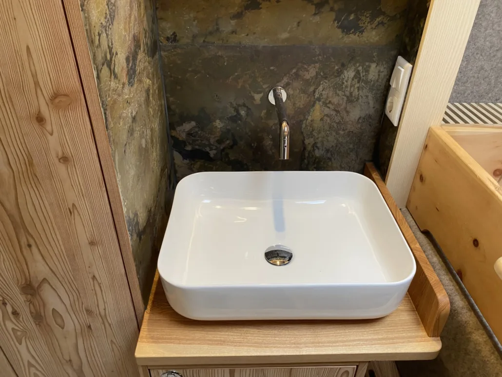 Aufsatzwaschbecken mit Wandarmatur auf dem Holzwaschtisch