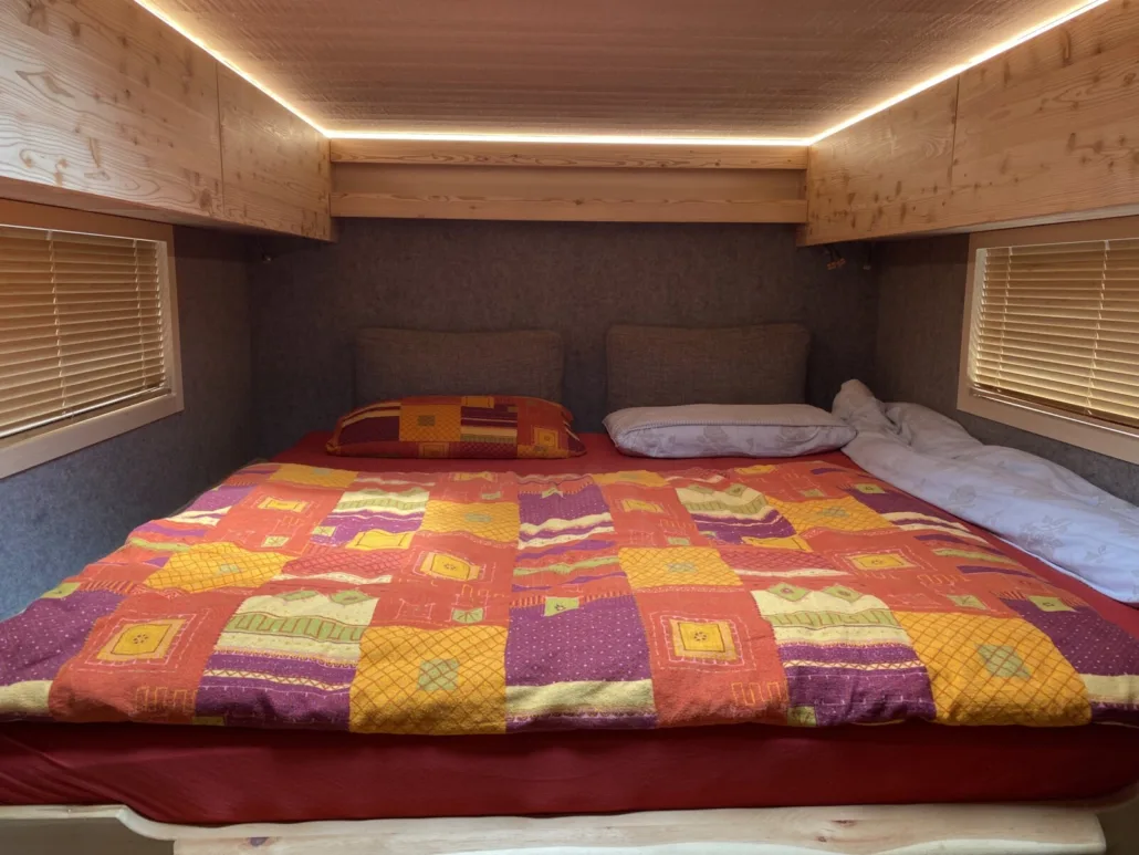 Fertiges Bett mit Patchwork-Decke, Oberschränken und LED-Beleuchtung